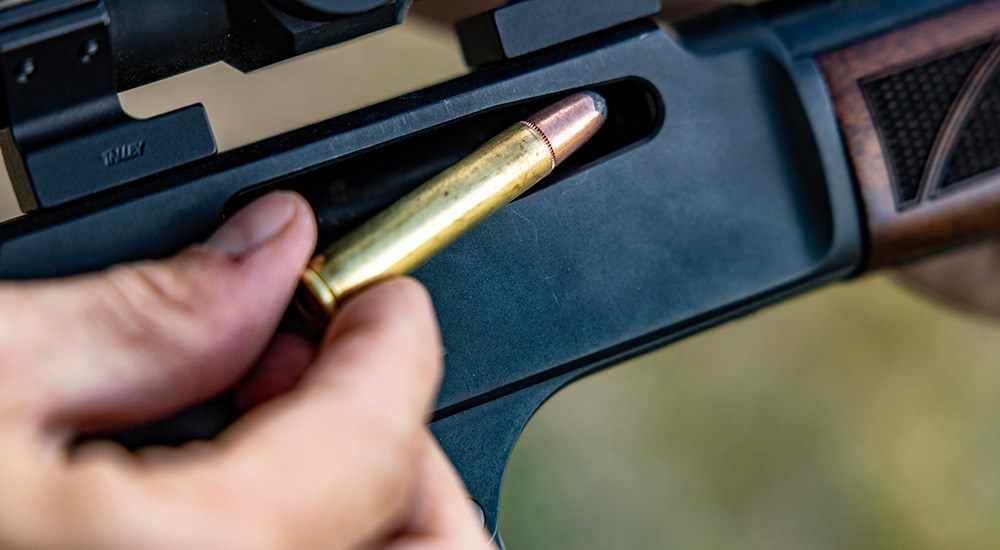 Remington 360 Buckhammer ammunition cartridge being loaded into lever action rifle.