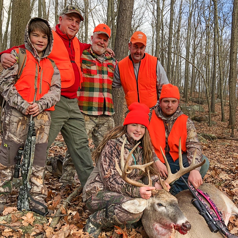 Young female hunter with family members and whitetail buck