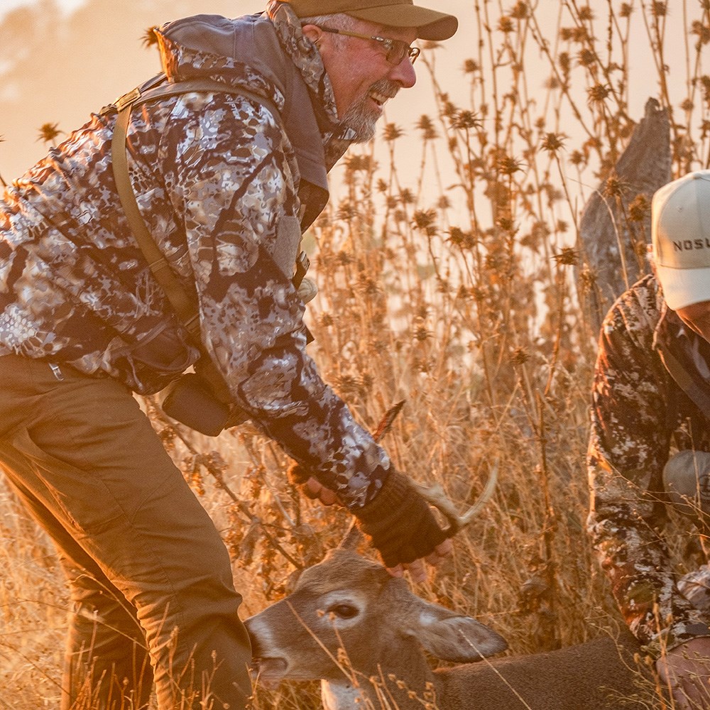 Male hunter dragging Columbian whitetail deer.