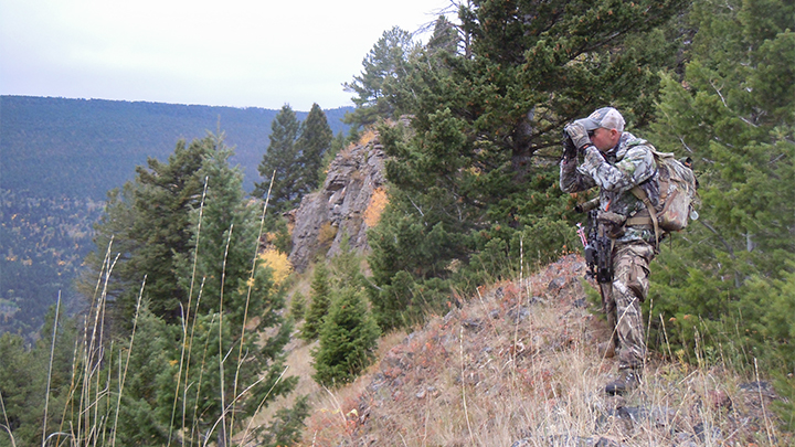Hunter using binocular at top of mountain