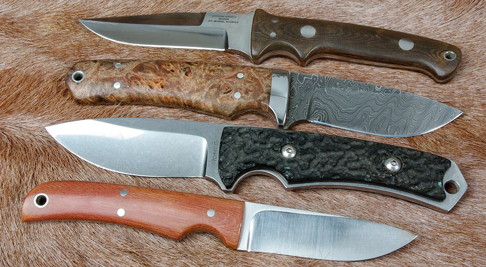 Various styles of fixed blade hunting knives on animal hide.