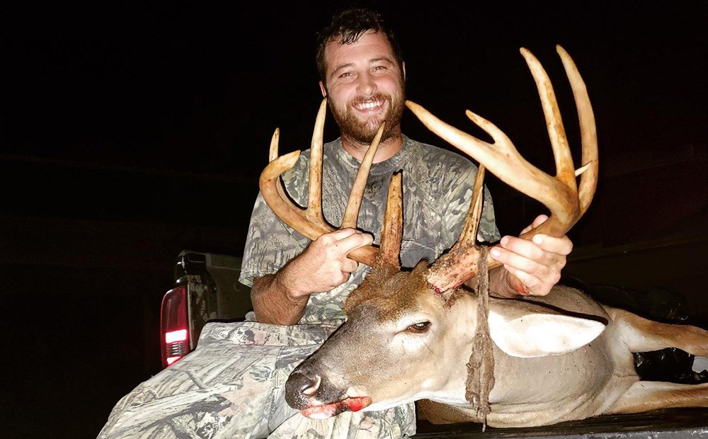 Male hunter holding large whitetail buck killed in Calhoun County, South Carolina.