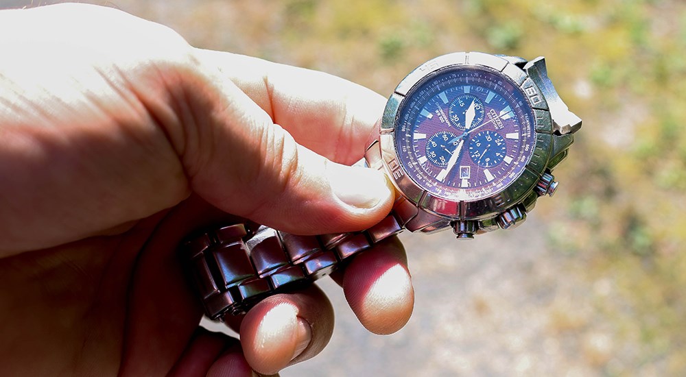 Wristwatch in hand being used to discover direction.