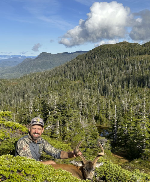 Hunter with deer in vast landscape